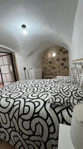 ein Schlafzimmer mit einem schwarz-weißen Bett in einem Zimmer in der Unterkunft Encantadora casa en Aroche in Aroche