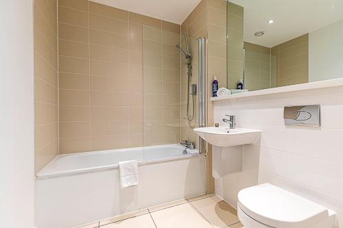 a bathroom with a tub and a toilet and a sink at Stepney Green City Apartment in London