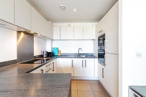 a kitchen with white cabinets and a sink at Stepney Green City Apartment in London