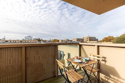 a balcony with a table and chairs on a roof at Stepney Green City Apartment in London