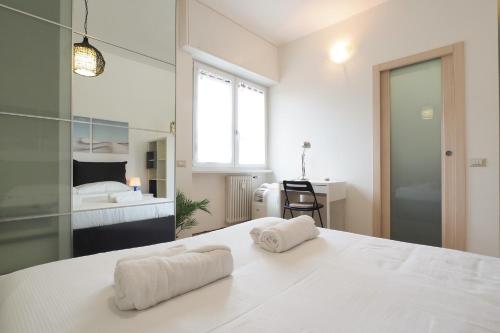 a white bedroom with two towels on a bed at Primopiano - Avogadro in Milan