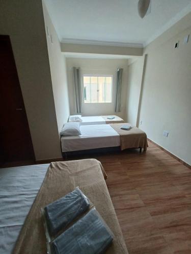 Habitación grande con 2 camas y ventana. en Pousada Estrela Mares Suíte 208, en Cabo Frío