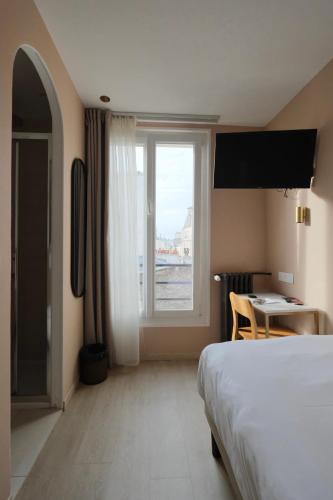 a bedroom with a bed and a desk and a window at Hipotel Paris Père-Lachaise République in Paris