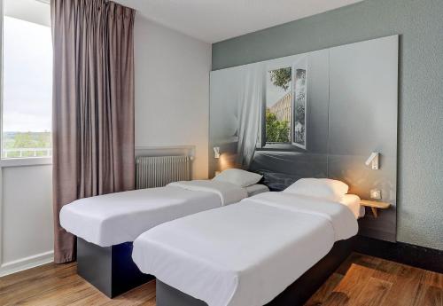 ショーモンにあるB&B HOTEL Chaumontのベッド3台 ホテルルーム 窓付