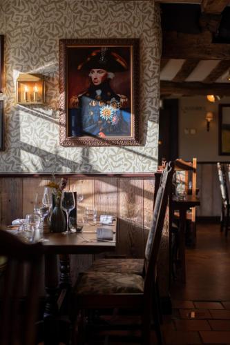a dining room with a painting of a man on the wall at The Crown Inn in Bishops Waltham