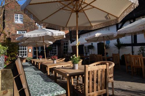 a row of tables and chairs with umbrellas at The Crown Inn in Bishops Waltham