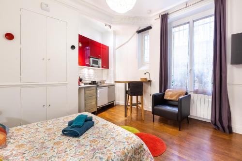 Cet appartement comprend une chambre avec un lit et une cuisine avec des placards rouges. dans l'établissement Studio Saint Sulpice, à Paris