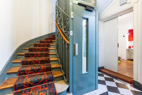 un escalier avec une porte bleue et des tapis colorés dans l'établissement Studio Saint Sulpice, à Paris