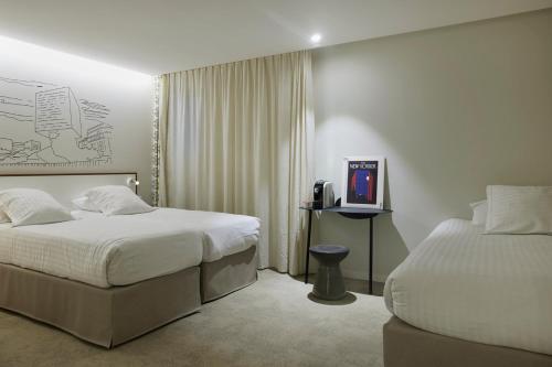 a hotel room with two beds and a television at Hotel du Pin Nice Port in Nice