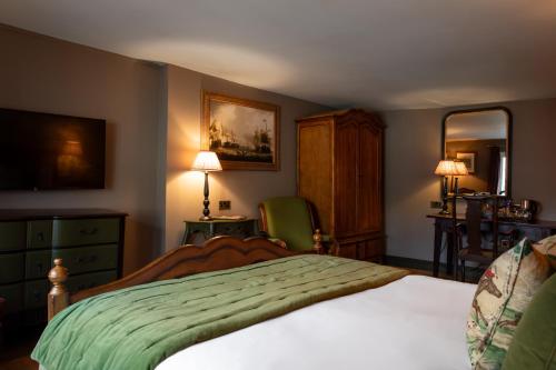 a bedroom with a bed and a dresser and a mirror at The Crown Inn in Bishops Waltham