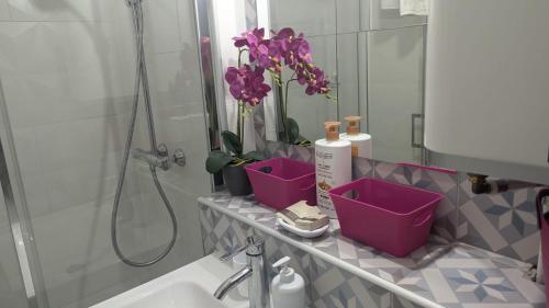 La salle de bains est pourvue d'un lavabo, d'un miroir et de fleurs violettes. dans l'établissement Central Mont Blanc View Apartment, balcony, free parking, à Chamonix-Mont-Blanc