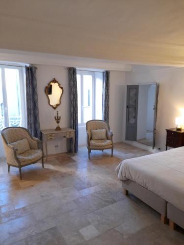 a bedroom with two chairs and a bed and windows at La Tour de Pezene in Anduze