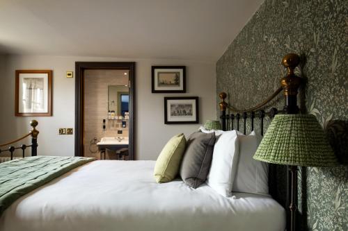 a bedroom with a large white bed with a lamp at The Crown Inn in Bishops Waltham