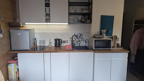 une cuisine avec des placards blancs et un comptoir avec un four micro-ondes dans l'établissement Central Mont Blanc View Apartment, balcony, free parking, à Chamonix-Mont-Blanc
