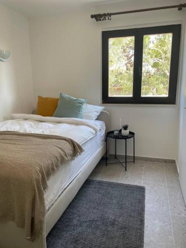 a white bedroom with a bed and a window at Villa L.L in Splitska