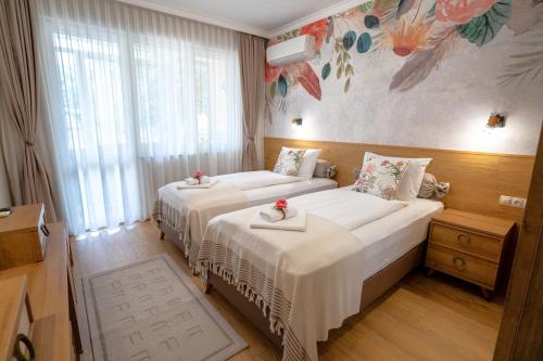 two beds in a hotel room with flowers on the wall at SP Urban Apartment in Plovdiv