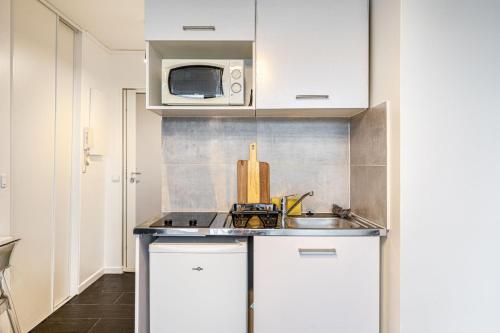 une cuisine avec un évier et un micro-ondes dans l'établissement GuestReady - Elevated Comfort with a Terrace!, à Paris