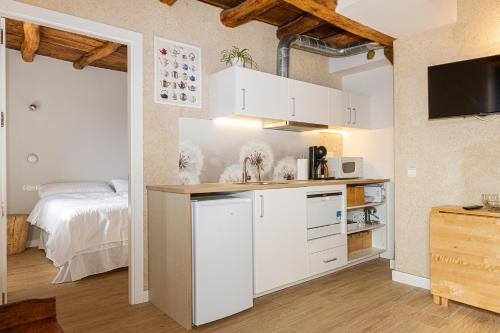 a kitchen with white cabinets and a bed in a room at Mokorroko Borda Hostal Rural in Echalecu