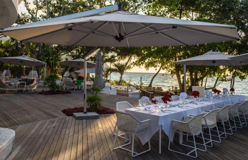 a table with white tables and chairs under an umbrella at Savoy Seychelles Resort & Spa in Beau Vallon
