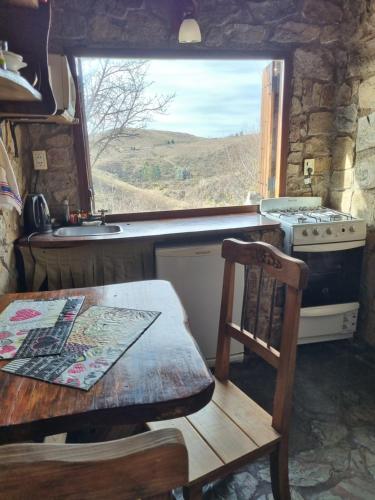 a kitchen with a table and a stove and a window at Estancia Altos del Durazno in Estancia Grande