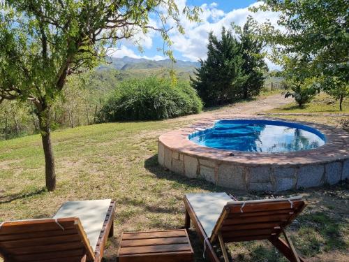 a swimming pool with two chairs and a table at Estancia Altos del Durazno in Estancia Grande
