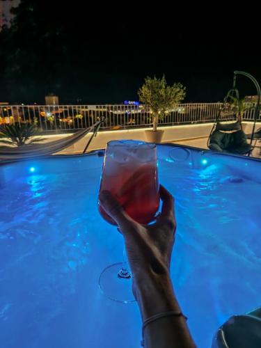a person holding a glass of wine in a swimming pool at Zadar Sunset Penthouse with spectacular view and jacuzzi in Zadar