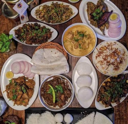 a table filled with different types of food on plates at Shivalaya Homestay, Madikeri in Siddapur