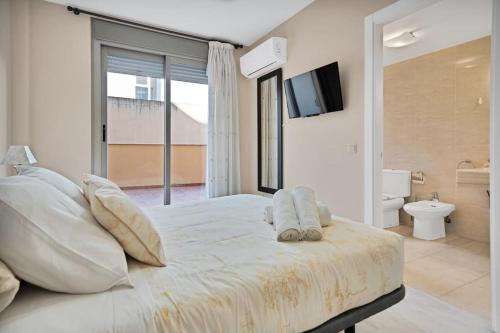 ein weißes Schlafzimmer mit einem großen Bett und einem Badezimmer in der Unterkunft Apartamento con terraza y piscina en Puerto Marina - MISTRAL in Benalmádena