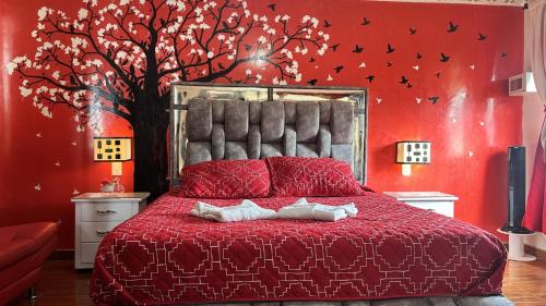 a bedroom with a red bed with a tree on the wall at Posada Martha Tolima in Salento