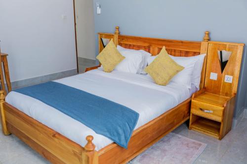 a bedroom with a wooden bed with white sheets and pillows at Heim Villa in Kahe