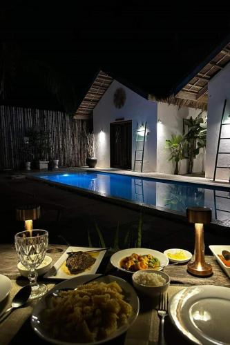 a table with plates of food next to a pool at Sirom Beach House in Tambobong
