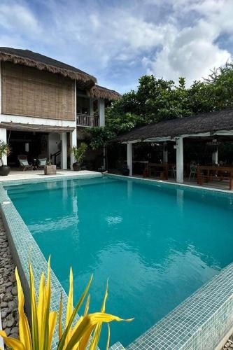 a large blue swimming pool next to a house at Sirom Beach House in Tambobong