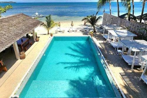 a swimming pool next to a beach with palm trees at Sirom Beach House in Tambobong
