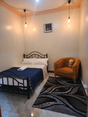 a bedroom with a bed and a chair at Quill homes in Fort Portal