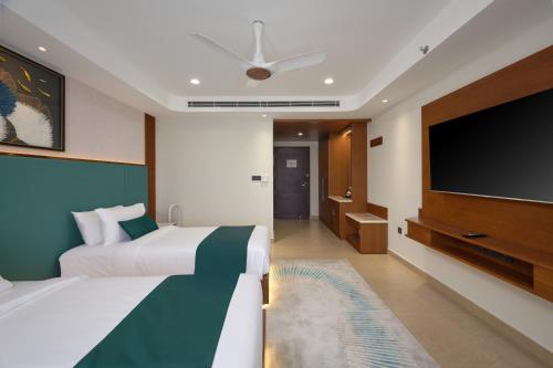 a bedroom with a large bed and a flat screen tv at Kowju Airport Hotel Calicut in Kondotti
