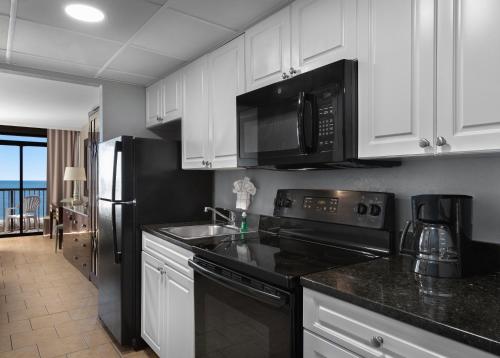 a kitchen with black appliances and white cabinets at Hotel Blue in Myrtle Beach