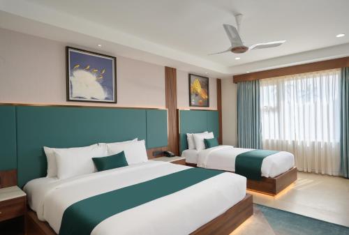 a hotel room with two beds and a window at Kowju Airport Hotel Calicut in Kondotti