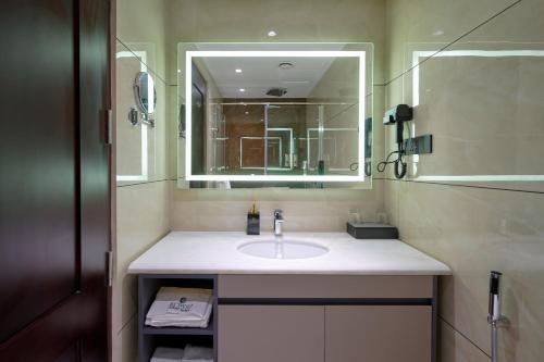 a bathroom with a sink and a mirror at Kowju Airport Hotel Calicut in Kondotti