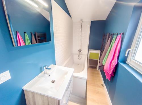 La salle de bains est pourvue d'un lavabo blanc et d'un mur bleu. dans l'établissement Maison à 10 min du centre dans avenue privée !, à Nantes
