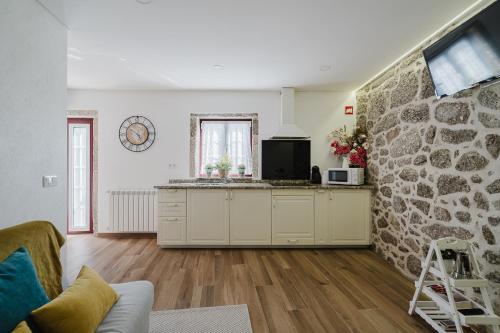 a kitchen with white cabinets and a stone wall at Casa Zé Manel - Turismo Rural in Paranhos