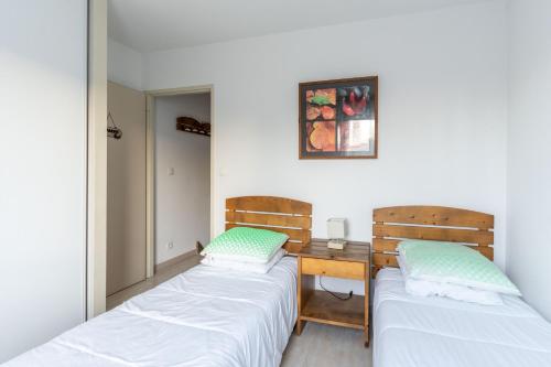 - 2 lits dans une chambre avec une table et un miroir dans l'établissement Bel appartement T3 dans résidence 3* à 50 m du lac, à Aureilhan