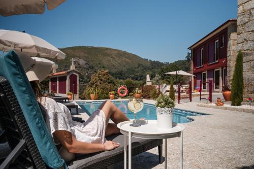 a woman sitting in a chair next to a pool at Casa Zé Manel - Turismo Rural in Paranhos