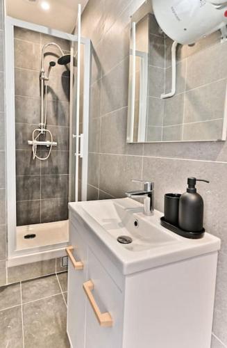 une salle de bain blanche avec un lavabo et une douche dans l'établissement Studio charmant tout équipé Paris Montreuil - IV, à Montreuil
