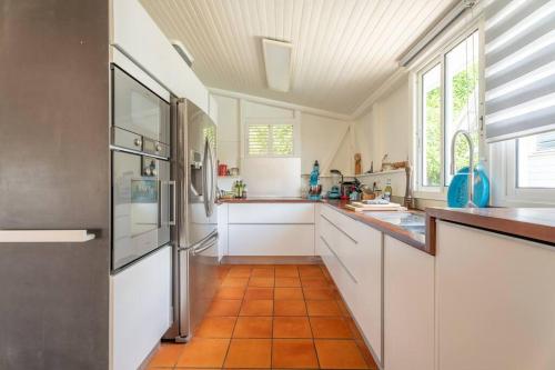 a kitchen with white cabinets and an orange tile floor at Villa Blue Rock, piscine & vue imprenable in Rivière-Salée