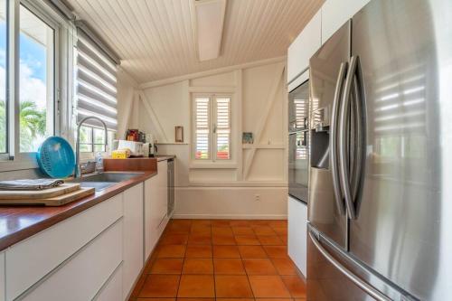 a kitchen with a stainless steel refrigerator and white cabinets at Villa Blue Rock, piscine & vue imprenable in Rivière-Salée