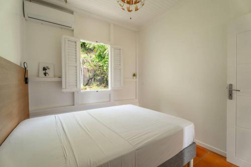 a white bedroom with a large bed and a window at Villa Blue Rock, piscine & vue imprenable in Rivière-Salée