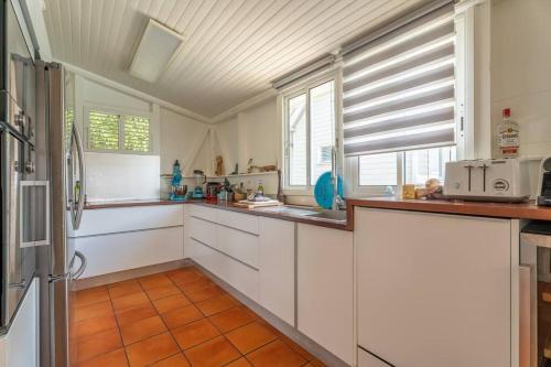 a kitchen with white cabinets and orange tile floors at Villa Blue Rock, piscine & vue imprenable in Rivière-Salée
