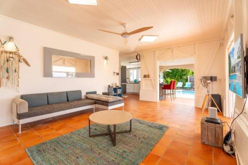 a living room with a couch and a table at Villa Blue Rock, piscine & vue imprenable in Rivière-Salée