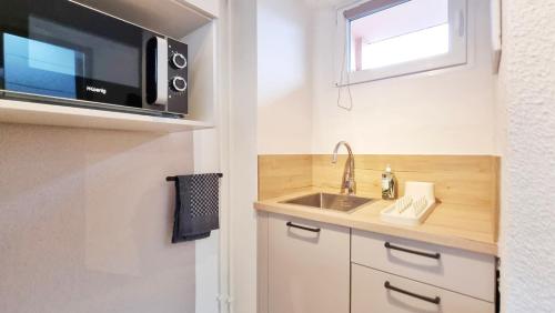 une cuisine avec un évier et un micro-ondes dans l'établissement Le Cozy Urbain - Centre - RBNB, à Colmar