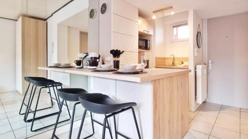 une cuisine avec quatre tabourets de bar à un comptoir dans l'établissement Le Cozy Urbain - Centre - RBNB, à Colmar